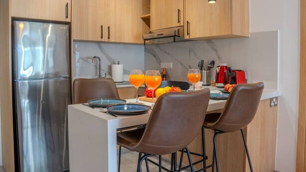 Eine moderne Küche mit Edelstahlgeräten, Holzschränken und einer zentralen Kochinsel mit Barhocker.