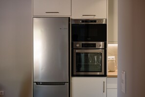 Una cocina con un refrigerador de acero inoxidable, horno integrado y microondas.