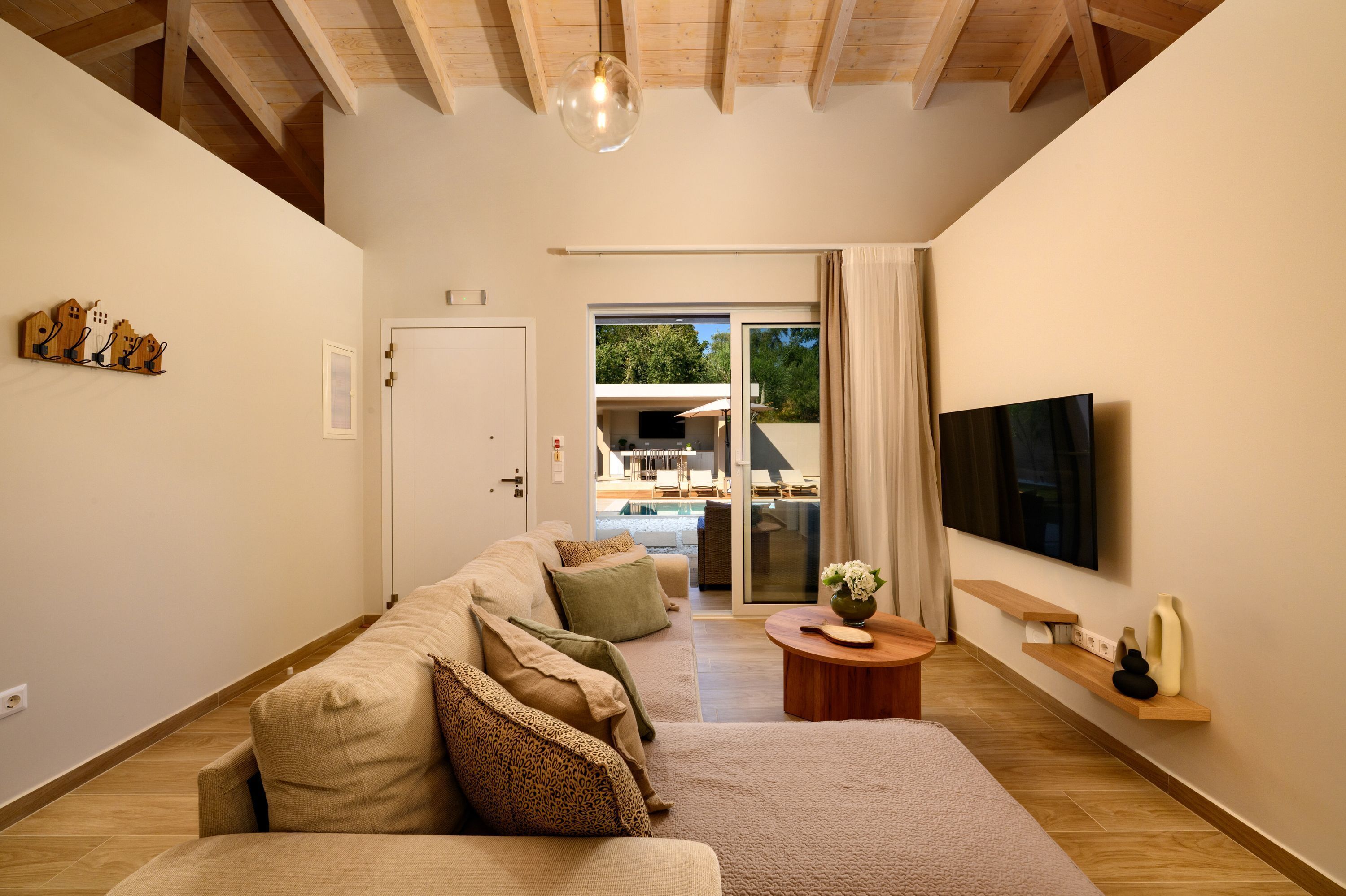 Una sala moderna con un sofá, un televisor de pantalla plana y techo de madera.