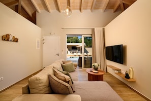 Uma sala de estar moderna com um sofá, uma TV de tela plana e teto de madeira.