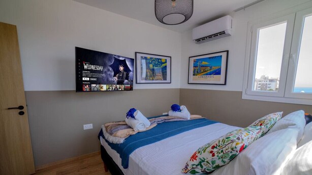 A bedroom with a bed, a TV mounted on the wall, and a window. - 4.97 Super Host`s New Boutique & Prime Location (Limassol)