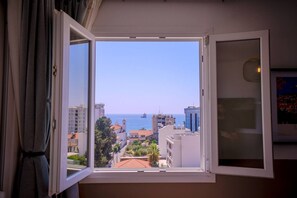 A room with a window overlooking a coastal cityscape, including buildings and a clear sky. - 4.97 Super Host`s New Boutique & Prime Location (Limassol)