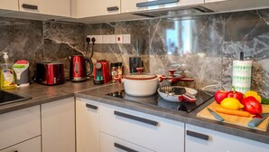 A modern kitchen with white cabinets, a marble backsplash, and various appliances including a red toaster, a kettle, and a slow cooker. - 4.97 Super Host`s New Boutique & Prime Location (Limassol)