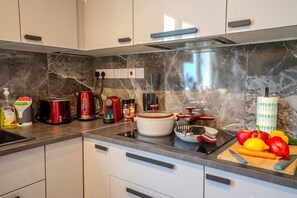 A modern kitchen with white cabinets, a marble backsplash, and various appliances including a red toaster, a kettle, and a slow cooker. - 4.97 Super Host`s New Boutique & Prime Location (Limassol)