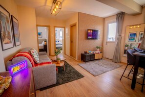 Un salon moderne comprenant un canapé, une table basse, un téléviseur et un coin repas avec une chaise.