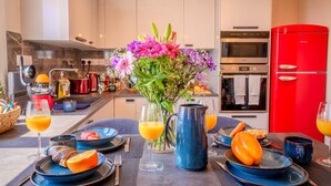 A modern kitchen with a dining area set for breakfast, including plates, cutlery, and a vase of flowers. - 4.97 Super Host`s New Boutique & Prime Location (Limassol)