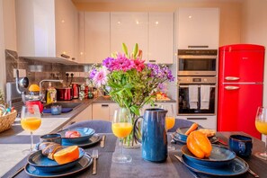 A modern kitchen with a dining area set for breakfast, including plates, cutlery, and a vase of flowers. - 4.97 Super Host`s New Boutique & Prime Location (Limassol)