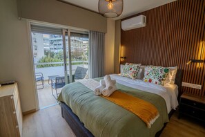Ein Hotelzimmer mit Bett, Schreibtisch, Stuhl und einem Balkon mit Blick auf Gebäude.