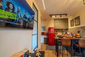 Une cuisine moderne avec un réfrigérateur rouge, un coin repas doté de tabourets de bar et une grande affiche accrochée au mur.