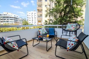 A balcony with two black lounge chairs, a small table, and a hanging chair with a colorful cushion. - 4.97 Super Host`s New Boutique & Prime Location (Limassol)