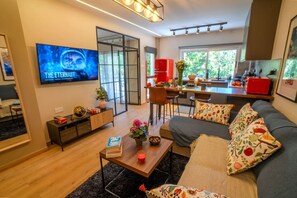 Een moderne woonkamer met een bank, salontafel en een televisie waarop 'The Eternaut' wordt weergegeven.