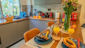 Una cucina moderna con zona pranzo, dotata di diversi elettrodomestici e vista sul verde.