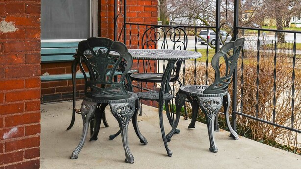 A patio with a table and chairs, a brick wall, and a metal fence.