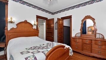 A bedroom with a wooden bed, a dresser, a mirror, and a chandelier.