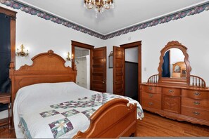 A bedroom with a wooden bed, a dresser, a mirror, and a chandelier.