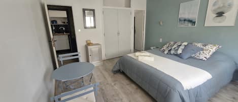 Une chambre à coucher avec un lit, une petite table, une chaise, une armoire et un miroir.