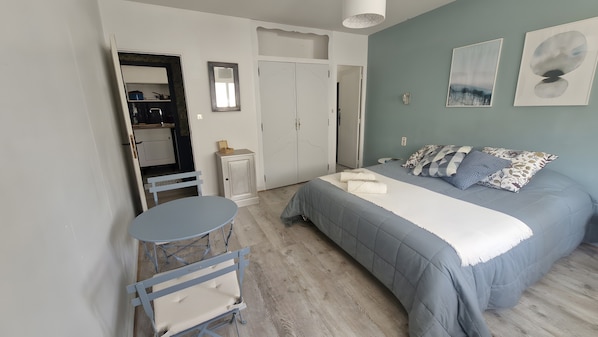 Une chambre à coucher avec un lit, une petite table, une chaise, une armoire et un miroir.