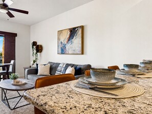 A dining area with a granite table, multiple bowls, and cutlery. - Cays Luxury Living! Resort Pool, Gym, Walk to Restaurants (Chandler)