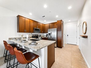 Eine moderne Küche mit Granit Arbeitsplatten, Edelstahlgeräten und Holzschränken.