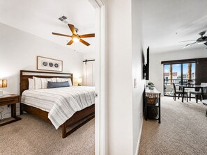 A bedroom with a bed, bedside tables, a ceiling fan, and a view of a balcony with a dining area. - Cays Luxury Living! Resort Pool, Gym, Walk to Restaurants (Chandler)