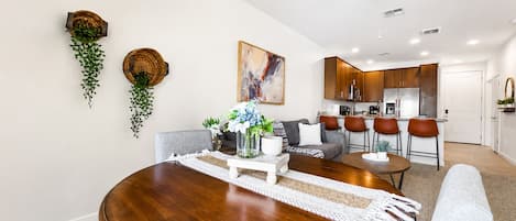 A dining area with a round wooden table, grey upholstered chairs, and a ceiling fan.