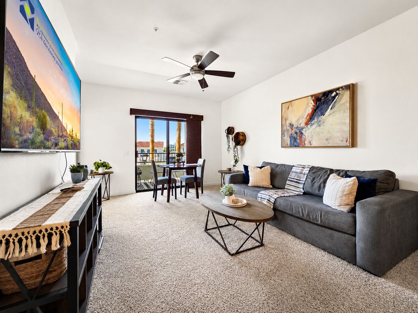A living room with a grey sofa, a coffee table, a TV, and a ceiling fan.
