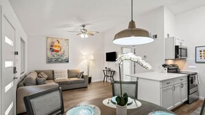 En moderne stue med sofa, spisebord og et køkkenområde.