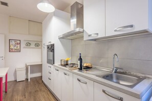A modern kitchen with white cabinetry, a stainless steel sink, and a built-in oven. - Palazzo Vecchio View by MMega (Firenze)