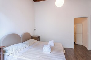 A bedroom with a bed, bedside tables, a lamp, and a door leading to another room. - Palazzo Vecchio View by MMega (Firenze)