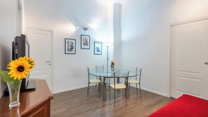 Un comedor con una mesa de vidrio y sillas, un jarrón con un girasol y cuadros en la pared.