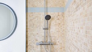 A shower with a handheld showerhead, a wall-mounted control panel, and a tiled wall. - BM – Élégance Parisienne & Vue sur Saint-Merri (Paris)