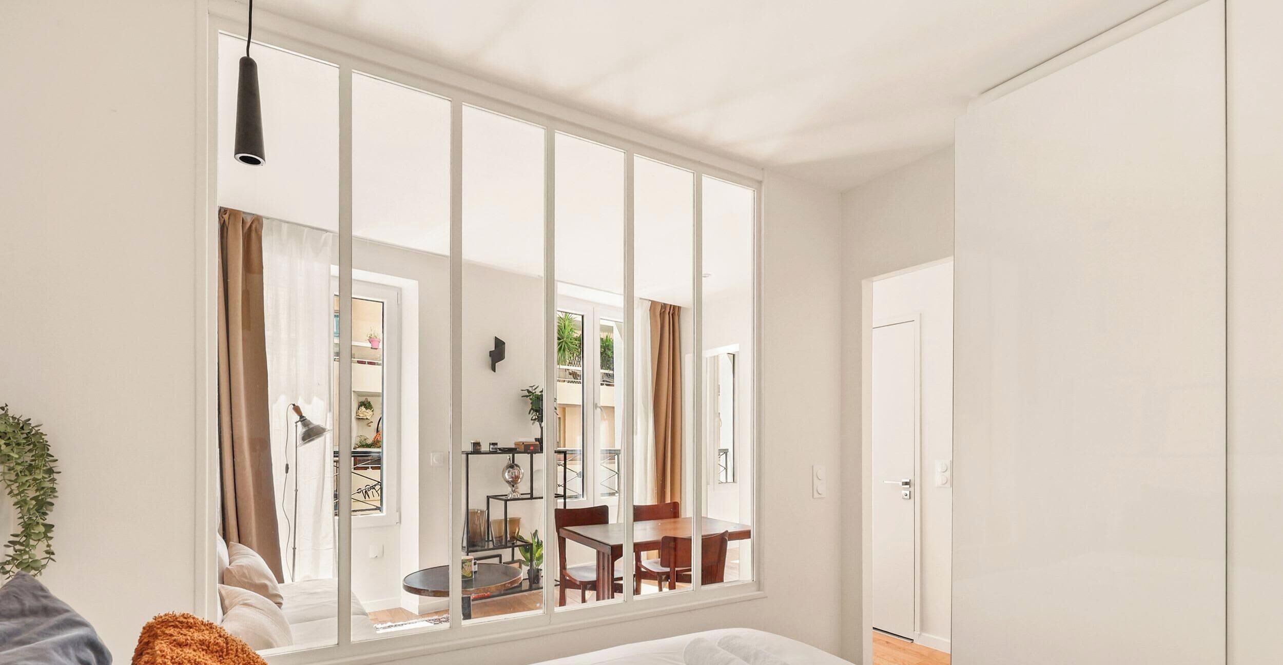 A modern room with a large window, a bed, a desk, and a chair.