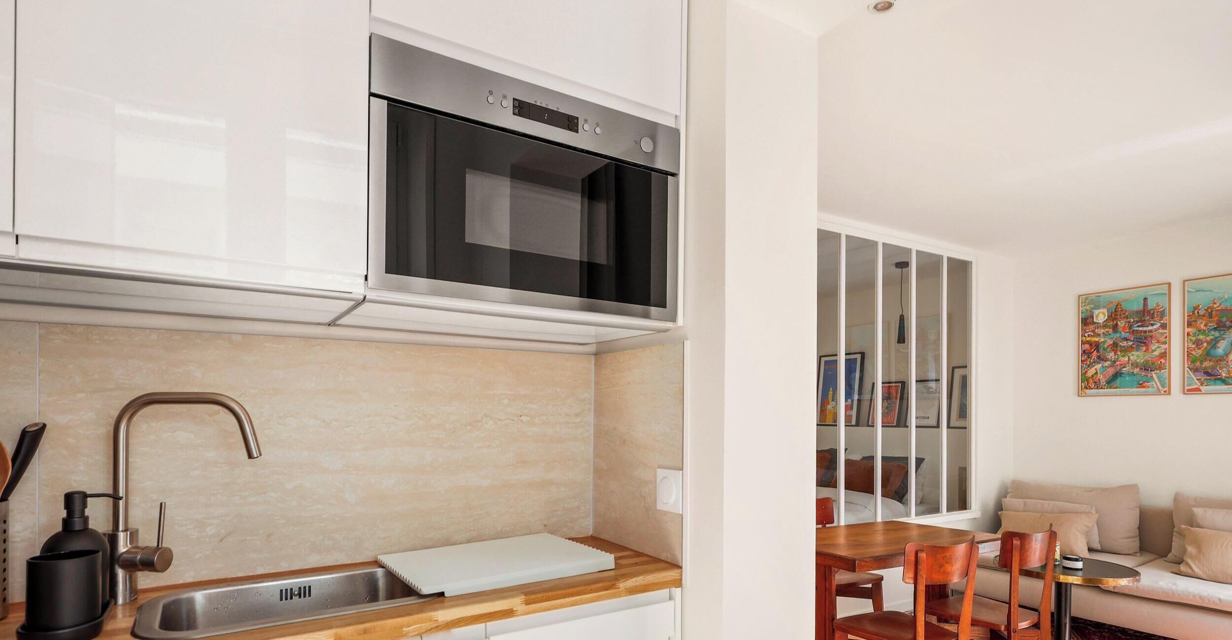 A modern kitchen with a stainless steel sink, a microwave, and a wooden countertop.