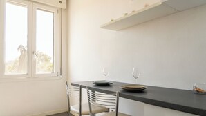 A modern kitchen with a dining table, two chairs, and a window.