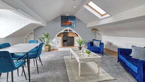A spacious loft with a dining area, seating, a fireplace, and a skylight. - Glendale House Two Bedroom Apt By Guestz (Lytham St Annes)