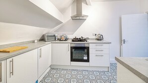 A modern kitchen with white cabinets, a built-in oven, a gas stove, a toaster, and a coffee maker. - Glendale House Two Bedroom Apt By Guestz (Lytham St Annes)