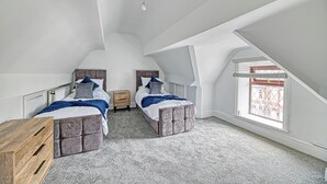 A bedroom with two beds, a wooden dresser, and a window with a view. - Glendale House Two Bedroom Apt By Guestz (Lytham St Annes)