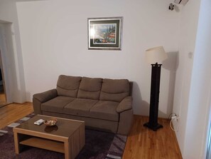 A living room with a brown sofa, a small wooden coffee table, a floor lamp, and a framed picture on the wall. - 2-bedroom apartment in center of Dubrovnik (Dubrovnik)