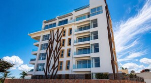 A multi-story building with a modern architectural design, featuring a prominent geometric facade and a series of balconies. - La Cruz Gem: Stunning Bay Views & Rooftop Pool, Located Close to Marina (Cruz de Huanacaxtle)
