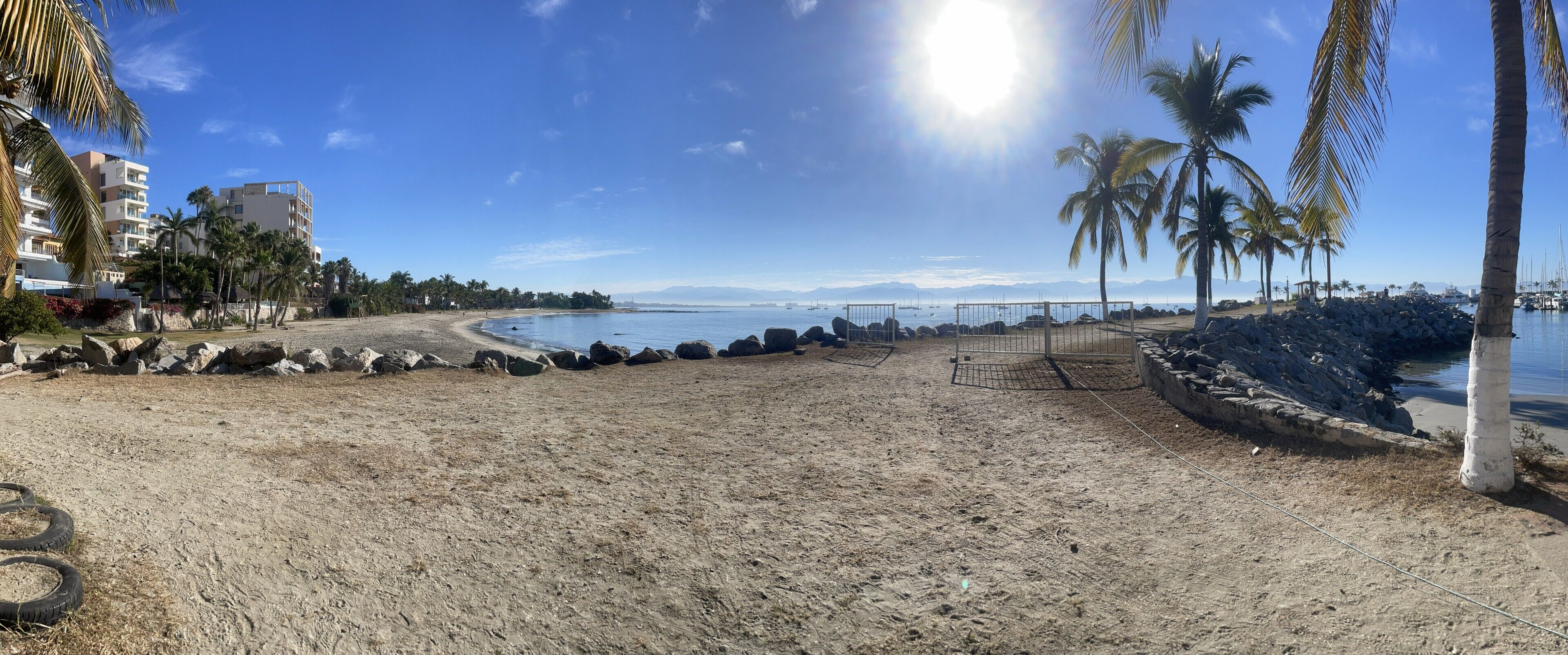 Ein Strand mit felsigem Ufer, Palmen und blauem Himmel.