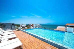Piscina en la azotea con vistas despejadas al océano y edificios circundantes.