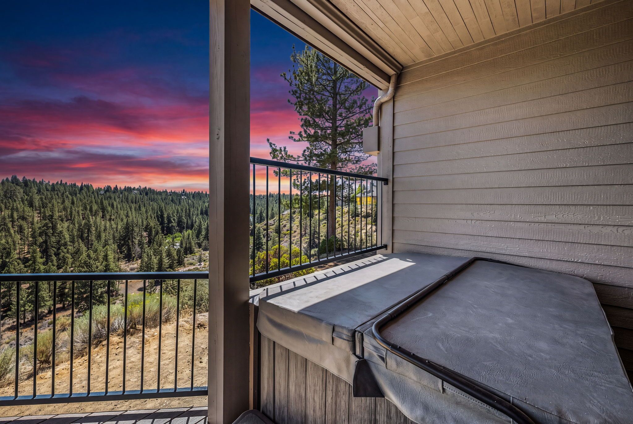 Ein Balkon mit Blick auf einen Wald und einen Sonnenuntergang.