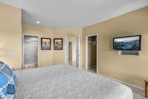 Quarto com uma cama, uma TV e duas portas que dão para outros espaços.