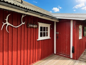 A red building with a white door and window, a sign reading 'STOLSBUE,' and a wooden deck. - A Charming Off-Grid Cabin – Close to Nature in Hemsedal (Hemsedal)