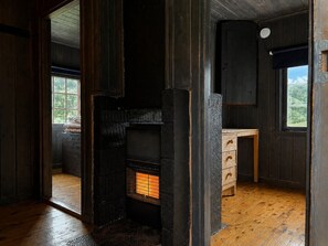Ein Zimmer mit Kamin, Holzwänden, einem Fenster und einem Holzschrank.