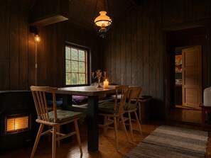 Una habitación acogedora con una mesa de madera, sillas, una vela encendida y una ventana con vistas.