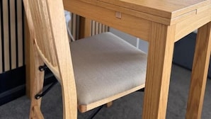 A wooden chair with a cushioned seat and backrest, positioned at a wooden table. - Aaron Wise - 09 Coldstream Studios (Cardiff)