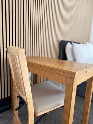 A wooden chair with a cushioned seat and backrest, positioned at a wooden table. - Aaron Wise - 09 Coldstream Studios (Cardiff)