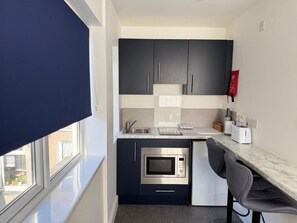 A compact kitchen with dark cabinets, a built-in microwave, and a small countertop.