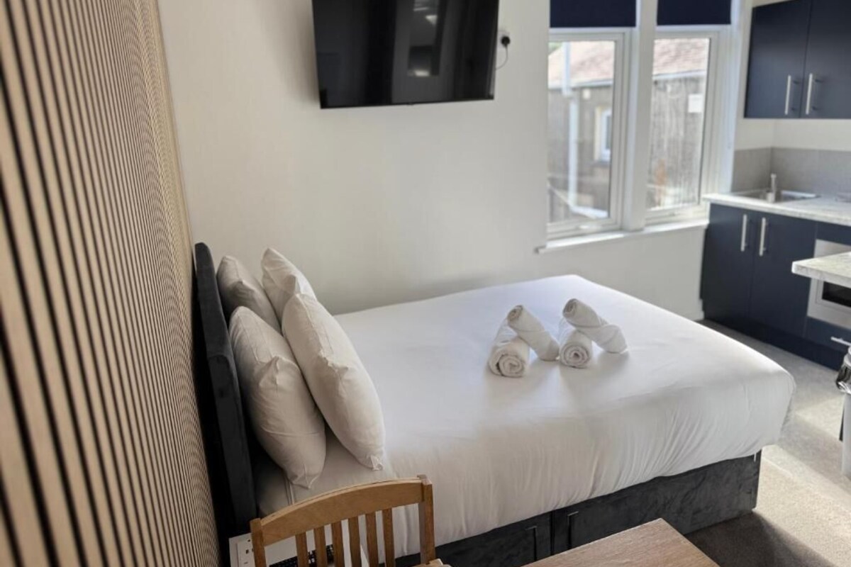 A hotel room with a bed, a television mounted on the wall, and a view of the outside through a window.